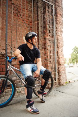 bisikletçi Bisiklet yakınındaki duvara oturan Güvenlik kask 