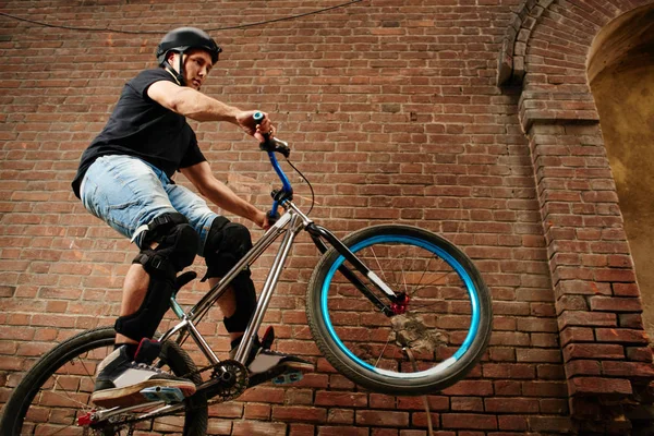 arka tekerlek kırmızı tuğla binanın duvarının yakınında bisiklet sürme bisikletçi
