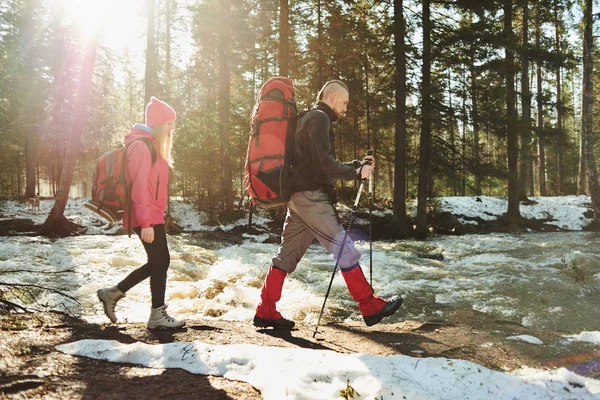 bahar ormandaki nehir üzerinde yürüyen sırt çantaları ile erkek ve dişi yürüyüşçü 