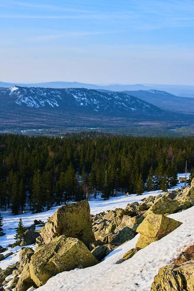 panoramic view of snowy mountains with woods at sunny day