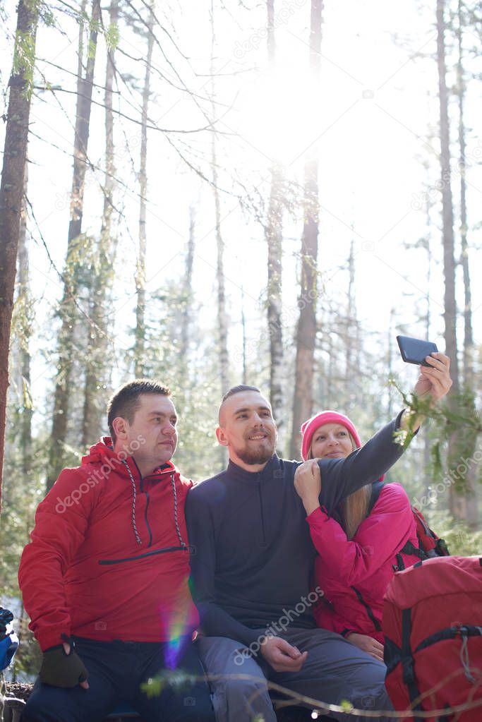 group of tourists taking selfies in woods at sunny day