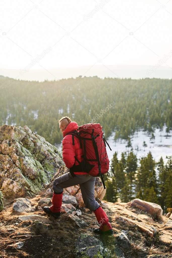 man with with rucksacks on backs climbing on top of sunlit mountain 