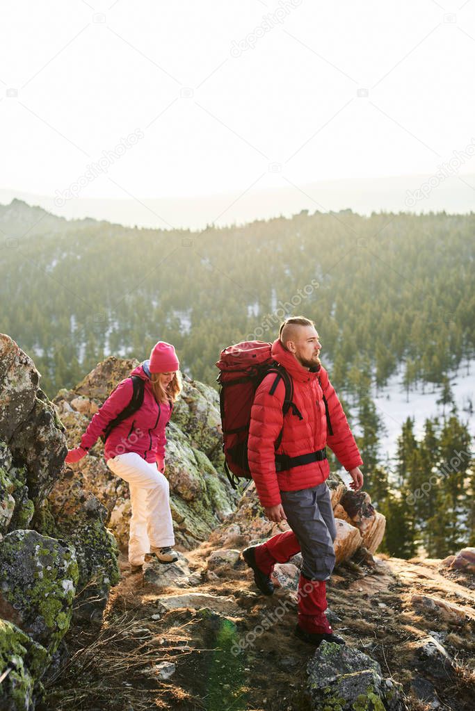 group of tourists consisting of woman and man coming down stone of cliff