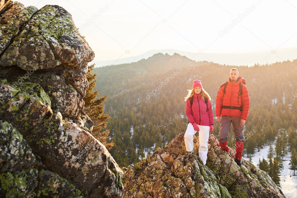 male and female tourists with backpacks standing on top of mountain
