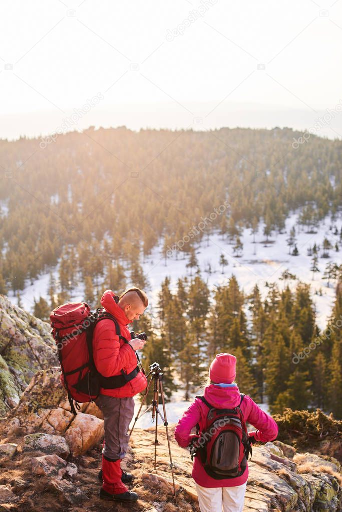 hikers with rucksacks on backs doing photos with tripod on top of mountain