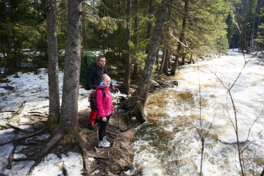 yürüyüşçü orman içinde akan nehri yakınında güneşli gün ayakta Turistik arka çantalar ile