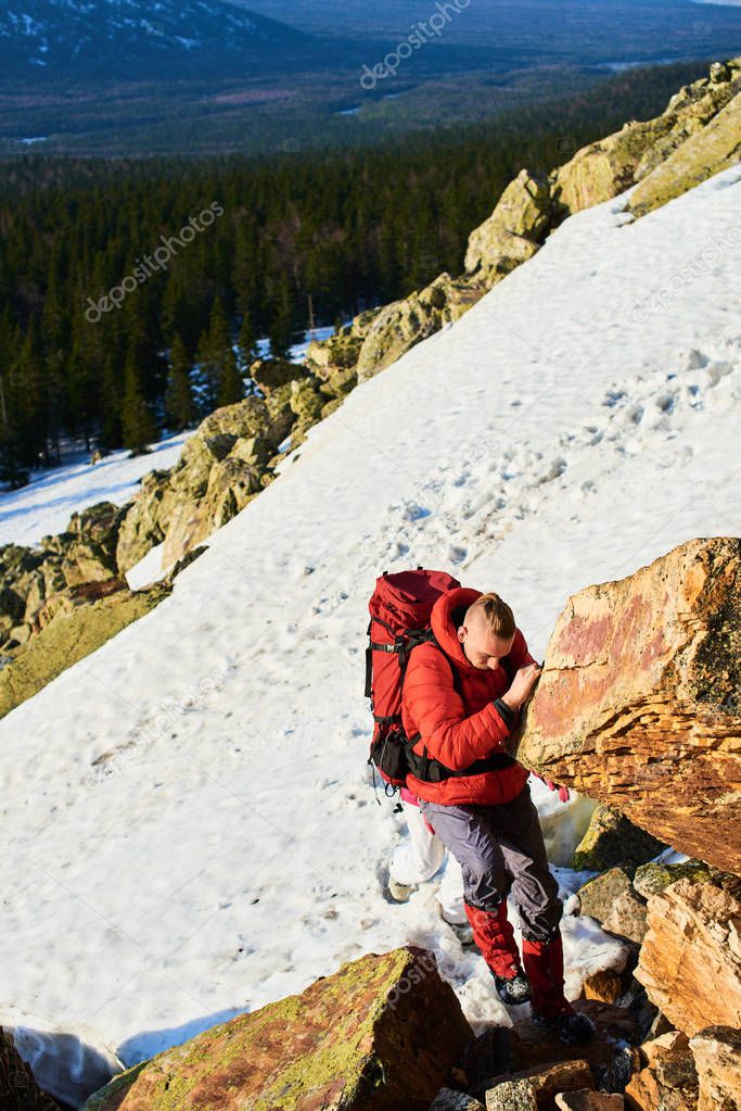 couple of hikers climbing on rocky mountain with snowy at spring