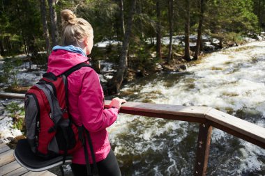 nehir üzerinde ahşap köprü üzerinde duran sırt çantası ile kadın turist 