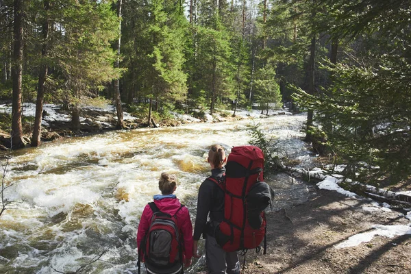 turist çift aşık kıyıda duran ve ormandaki akan nehir bakarak sırt çantaları 