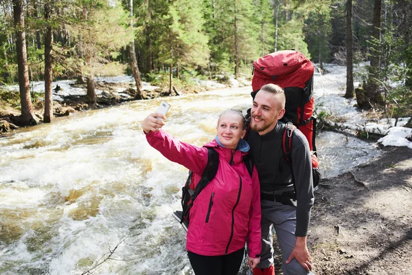 turist çift ormanda akan nehri yakınında selfies smartphone ile alarak aşık 
