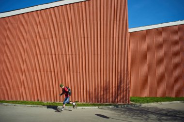 adam güneşli gün kırmızı duvar karşı hile yaparak silindirler üzerinde 