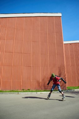 adam güneşli gün kırmızı duvar karşı hile yaparak silindirler üzerinde 