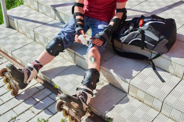 merdivenlerde oturan ve diz, ilk tıbbi yardım kavramı yaraya silerek paten erkekte 