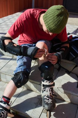 merdivenlerde oturan ve diz, ilk tıbbi yardım kavramı yaraya silerek paten erkekte 