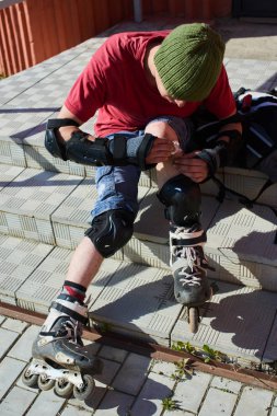 merdivenlerde oturan ve diz, ilk tıbbi yardım kavramı yaraya silerek paten erkekte 