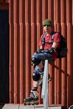 Tekerlekli paten merdiven korkuluk üzerinde oturan adam