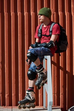 Tekerlekli paten merdiven korkuluk üzerinde oturan adam