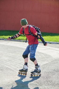 adam güneşli gün kırmızı duvar karşı hile yaparak silindirler üzerinde
