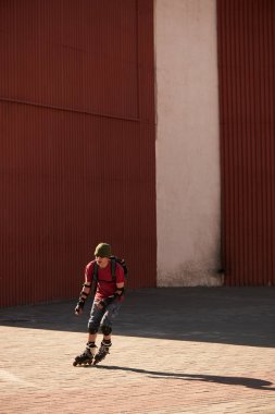 Bina arka plan üzerinde kırmızı patenci ile sırt silindir üzerinde sürme ekipman çantasında skates 