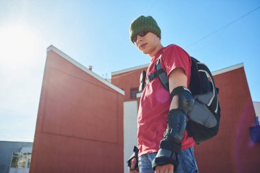 güneş gözlüğü ve şapka ayakta kırmızı binalar yakınındaki güneşli gün, sırt çantası ile kendine güvenen adam 