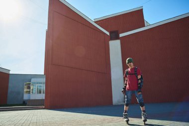 kendine güvenen adam tekerlekli paten ayakta kırmızı binalar yakınındaki 