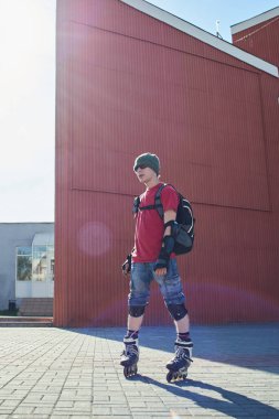 kendine güvenen adam tekerlekli paten ayakta kırmızı binalar yakınındaki 