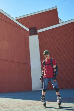 kendine güvenen adam tekerlekli paten ayakta kırmızı binalar yakınındaki 