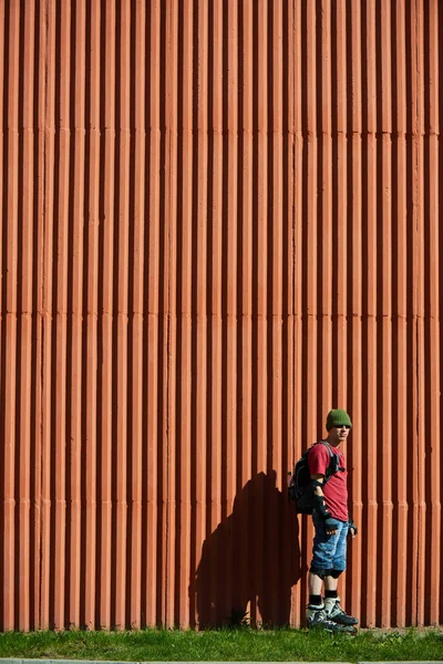 Patinador Sobre Rodillos Pie Sobre Hierba Verde Contra Pared Roja —  Fotos de Stock