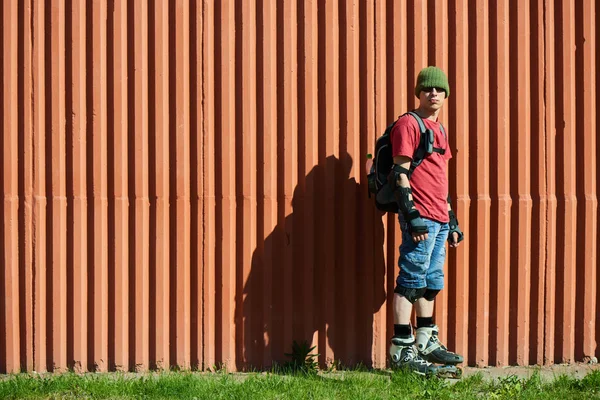 Patinador Sobre Rodillos Pie Sobre Hierba Verde Contra Pared Roja — Foto de Stock