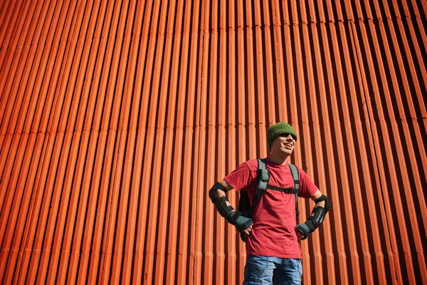 ekipman ile kırmızı duvar arka bina üzerinde sırt çantası duran adam 