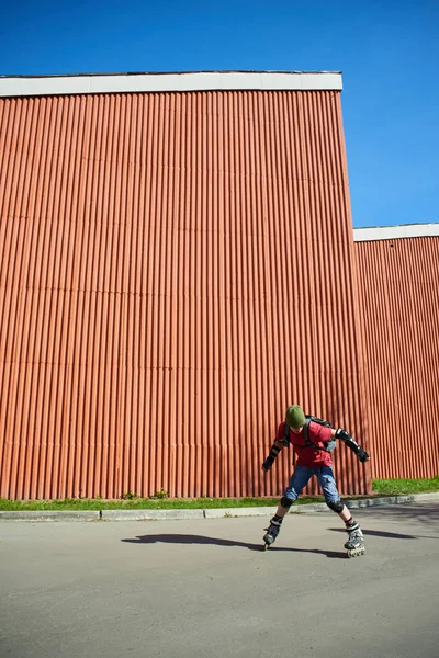 adam güneşli gün kırmızı duvar karşı hile yaparak silindirler üzerinde 