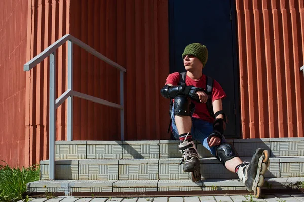 man in roller skates sitting on stairs of red building