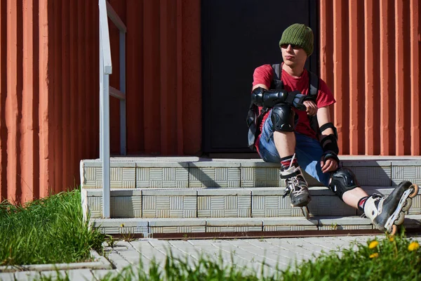 Tekerlekli paten kırmızı bina merdivenlerde oturan adam