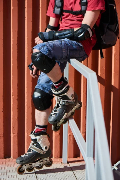 man in roller skates sitting on railing of stairs, close-up