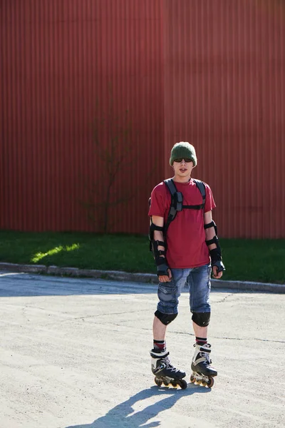 confident man in roller skates standing near red buildings