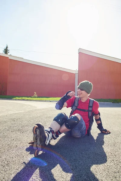 güneşli bir gün binaya yakın asfalt üzerinde oturan paten şık patenci 