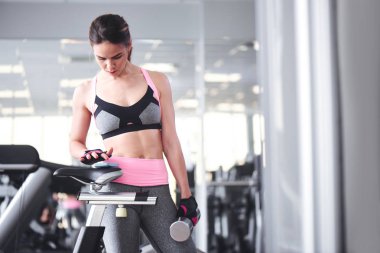 Spor salonunda duran Smartphone kullanan genç kadın 