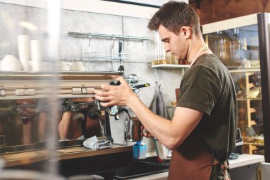 Barista kahve makinesi kapuçino işyeri için süt hazırlarken kullanarak önlük 