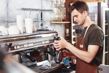 Barista kahve makinesi kapuçino işyeri için süt hazırlarken kullanarak önlük 