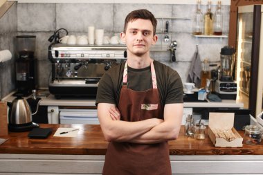 adam barista çapraz kollu ahşap bar yüzeyi kafede işyerinde yaslanmış