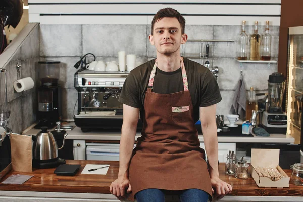 Man Barista Apron Sitting Wooden Bar Surface Workplace Coffee Shop — Stock Photo, Image