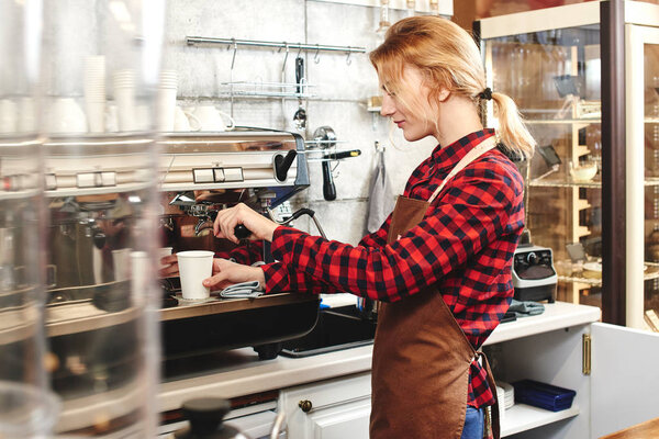 smiling attractive barista making coffee with coffee machine 