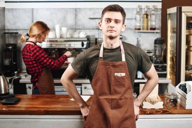 kameraya bakarak ve önünde duran yakışıklı barista kahve makinesi arka plan üzerinde yakınındaki meslektaşım olan çubuk 
