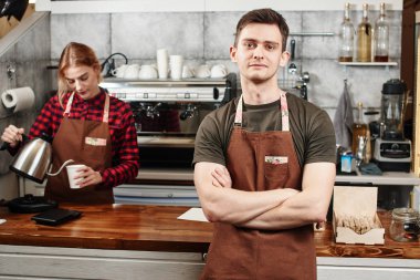 Erkek barista işyerinde kadın garson yakınındaki çapraz kolları olan ayakta 