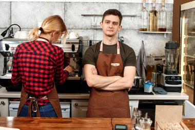 Erkek barista işyerinde kadın garson yakınındaki çapraz kolları olan ayakta 
