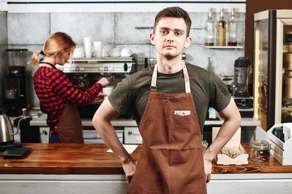 kameraya bakarak ve önünde duran yakışıklı barista kahve makinesi arka plan üzerinde yakınındaki meslektaşım olan çubuk 