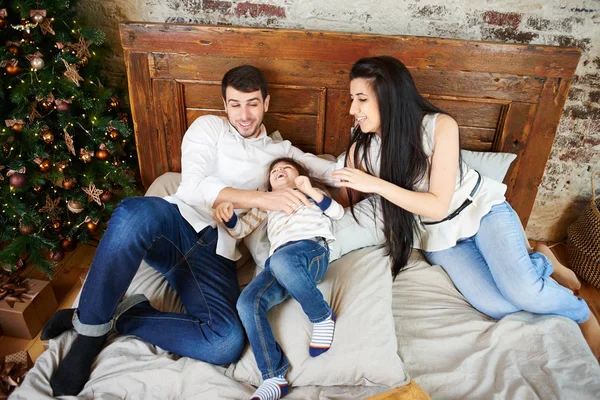happy asian family with son lying on bed in bedroom