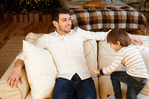 クリスマスの装飾のアパートのソファの上の父と遊ぶ子供 — ストック写真