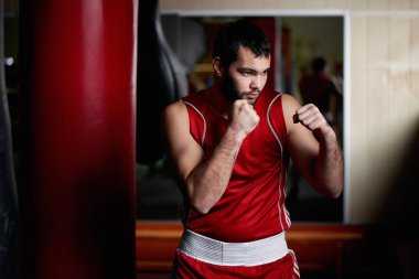 Boksta agresif Fighter portre arka plan üzerinde kum torbası ile spor salonunda 