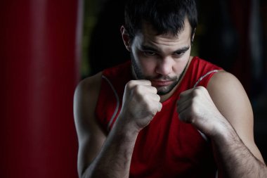 Boksta agresif Fighter portre arka plan üzerinde kum torbası ile spor salonunda 